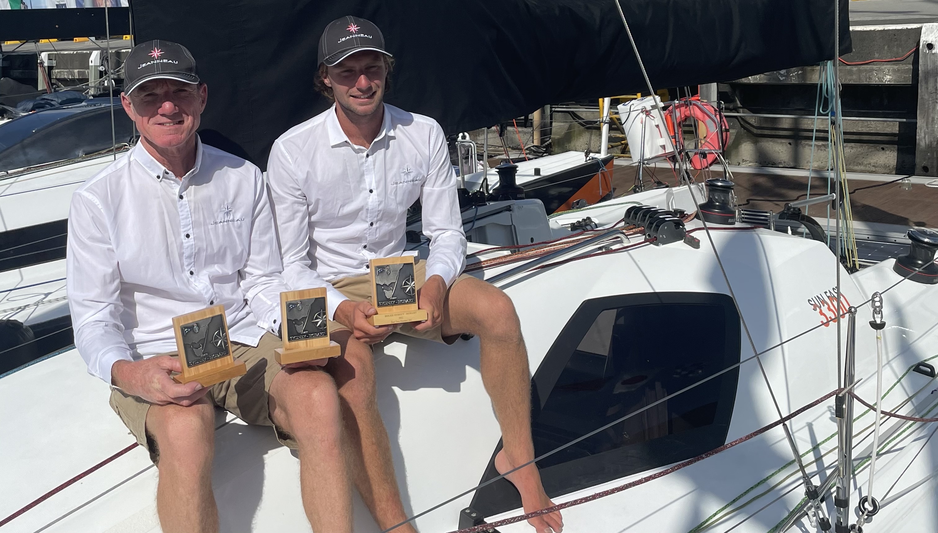 Lee Condell and a crew member in white shirts sitting on their boat holding his trophy